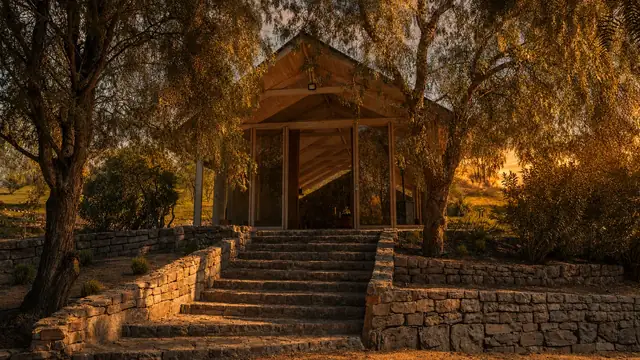 Capilla de Parque de Auco entre árboles y muros de piedra al atardecer